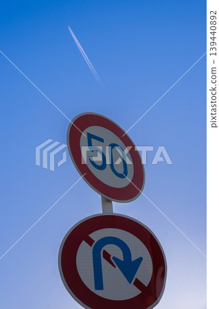 道路標誌,限速 50 公里/小時,禁止掉頭,藍天和飛機尾跡,交通規則,交通安全,材料。 道路標誌,限速 50 公里/小時,禁止掉頭,藍天和飛機尾跡,交通規則,交通安全,材料。 139440892