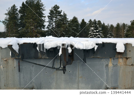 An automatic coupling for wagons is shown mounted on a concrete structure in a snowy environment surrounded by trees An automatic coupling for wagons is shown mounted on a concrete structure in a snowy environment surrounded by trees 139441444