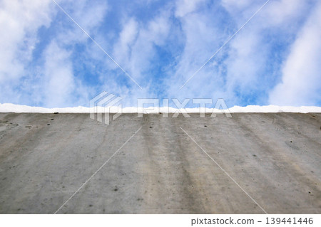 Blue sky with clouds visible from the top of a concrete surface under daylight. The scene shows textures of concrete and sky Blue sky with clouds visible from the top of a concrete surface under daylight. The scene shows textures of concrete and sky 139441446