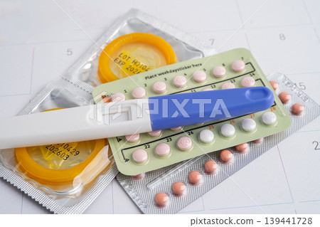 Pregnancy test and condom for female on calendar, ovulation day. Pregnancy test and condom for female on calendar, ovulation day. 139441728