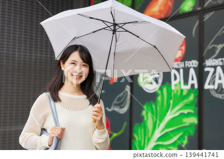 一位年輕女子撐著陽傘去超市。 139441741