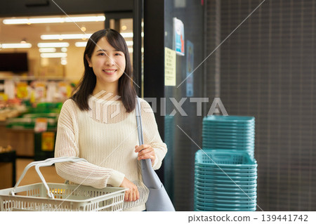 一位年輕女子提著購物籃在超市購物。 139441742