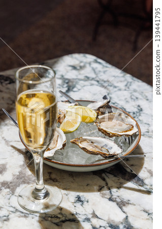 Fresh oysters on ice with champagne in sunlight Fresh oysters on ice with champagne in sunlight 139441795