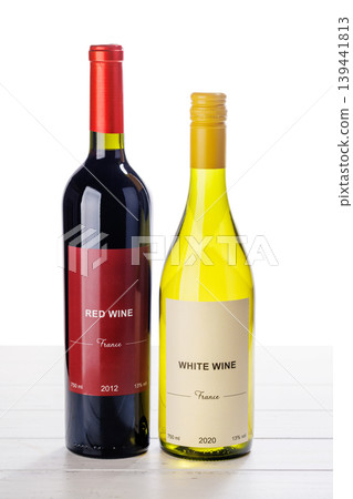 Red and white wine bottles on wooden table 139441813
