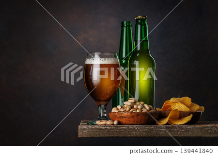 Beer glass with foam and bottles with pistachios Beer glass with foam and bottles with pistachios 139441840