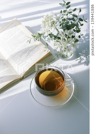 Morning light, tea, white flowers, and a peaceful time with a book. 139441886