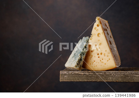 Cheese pieces on rustic wooden table dark background Cheese pieces on rustic wooden table dark background 139441986