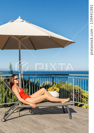 Woman sunbathing on veranda with ocean view 139441991