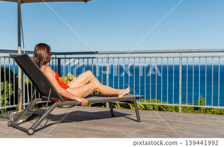 Woman sunbathing on veranda with ocean view 139441992