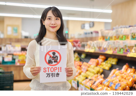 A young woman holding an anti-shoplifting sign in front of products in a supermarket. A young woman holding an anti-shoplifting sign in front of products in a supermarket. 139442029