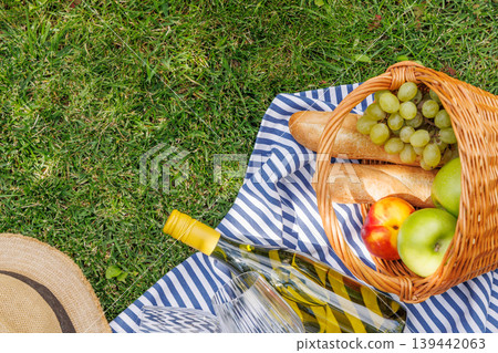 Picnic with wine, fruits, and baguette on a green meadow Picnic with wine, fruits, and baguette on a green meadow 139442063