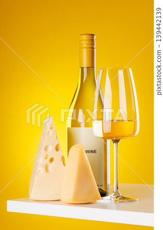 White wine with cheese pieces on yellow background gourmet composition 139442139
