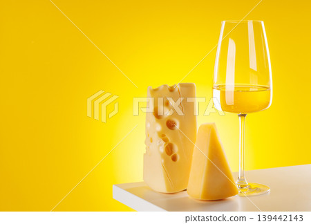 Glass of white wine with cheese on yellow background food pairing concept Glass of white wine with cheese on yellow background food pairing concept 139442143