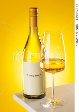 White wine bottle and glass on yellow background elegant drink setup White wine bottle and glass on yellow background elegant drink setup 139442144