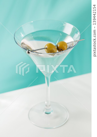 Classic martini cocktail with olives in glass on blue background Classic martini cocktail with olives in glass on blue background 139442154