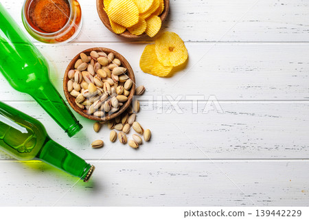 Beer bottles with pistachios and chips on white table Beer bottles with pistachios and chips on white table 139442229