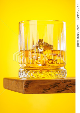 Whiskey glass with ice on yellow background minimal drink still life Whiskey glass with ice on yellow background minimal drink still life 139442238