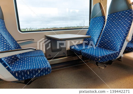 Interior of a deutsche bahn regional train carriage with empty blue seats and a table by the window. Interior of a deutsche bahn regional train carriage with empty blue seats and a table by the window. 139442271