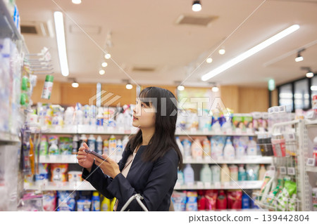 A businesswoman shopping at a supermarket while looking at notes on her smartphone. A businesswoman shopping at a supermarket while looking at notes on her smartphone. 139442804
