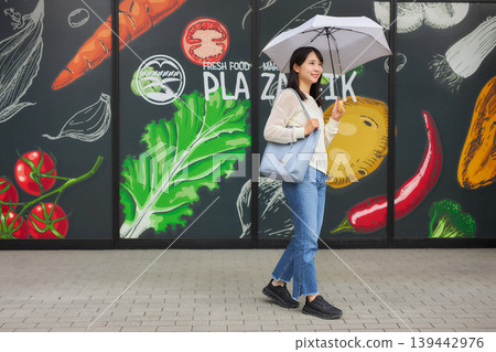 A young woman goes to the supermarket with a parasol. A young woman goes to the supermarket with a parasol. 139442976