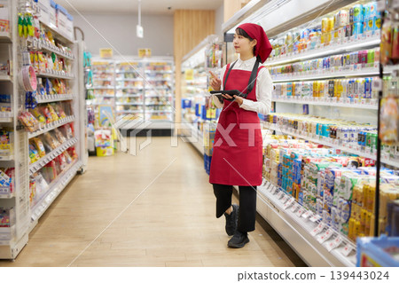A young woman manages products using a tablet. A young woman manages products using a tablet. 139443024