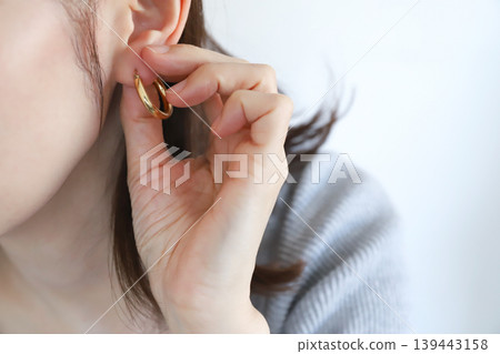 一位女士戴著耳環的耳垂。 一位女士戴著耳環的耳垂。 139443158