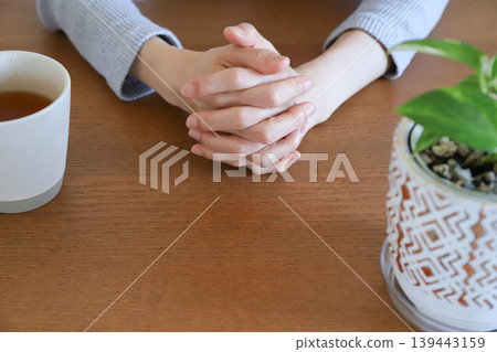 A woman's hands clasped together in thought. A woman's hands clasped together in thought. 139443159