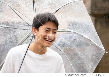 一個笑容燦爛的男孩撐著傘 一個笑容燦爛的男孩撐著傘 139445168