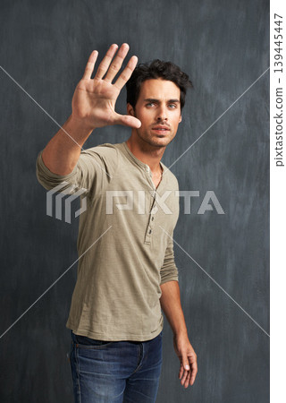 Serious, hand and portrait of man with stop for no, wait or rejection expression by wall. Upset, scared and young male person from Canada with casual style and fear palm gesture by gray background. Serious, hand and portrait of man with stop for no, wait or rejection expression by wall. Upset, scared and young male person from Canada with casual style and fear palm gesture by gray background. 139445447