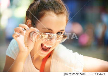 Woman, portrait and sunglasses for outdoor wink fun at summer festival in nature for camping, social gathering or explore holiday. Female person, face and eyewear for sunny, travel or happy adventure Woman, portrait and sunglasses for outdoor wink fun at summer festival in nature for camping, social gathering or explore holiday. Female person, face and eyewear for sunny, travel or happy adventure 139445621