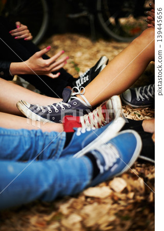 Sneakers, legs and friends on the ground outdoor in autumn together to relax or chill closeup. Fashion, style and casual with the shoes of a group of people sitting on leaves during the fall season Sneakers, legs and friends on the ground outdoor in autumn together to relax or chill closeup. Fashion, style and casual with the shoes of a group of people sitting on leaves during the fall season 139445656