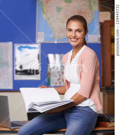 Happy woman, book and portrait of teacher sitting on desk in classroom for education or moderating. Female person, mentor or educator smile with notebook for marking, assessment or class agenda Happy woman, book and portrait of teacher sitting on desk in classroom for education or moderating. Female person, mentor or educator smile with notebook for marking, assessment or class agenda 139445732