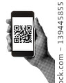 Hand holding a smartphone with QR code on the screen isolated on transparent background with vintage newspaper print texture. Concept of digital payment, scanning technology and mobile communication 139445855