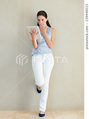 Woman, tablet and shocked on social media, news or gossip leaning against a wall at home. Surprised female person, brunette or freelancer gasping on technology for notification, alert or information Woman, tablet and shocked on social media, news or gossip leaning against a wall at home. Surprised female person, brunette or freelancer gasping on technology for notification, alert or information 139446015