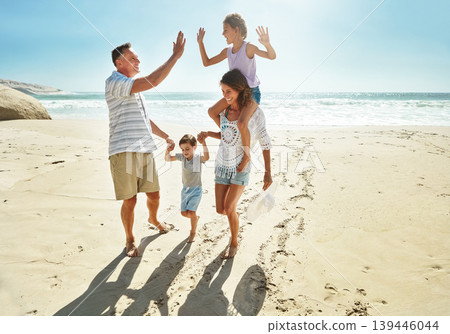 Parents, children and beach for high five in summer for travel vacation, ocean sunshine or sibling development. Man, woman and kids on sand for holiday relax walking or outdoor, clean air or smile Parents, children and beach for high five in summer for travel vacation, ocean sunshine or sibling development. Man, woman and kids on sand for holiday relax walking or outdoor, clean air or smile 139446044