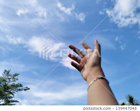 A hand in front of beautiful blue sky with white cumulus clouds 139447048