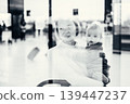 Thoughtful young mother looking trough window holding his infant baby boy child while waiting to board an airplane at airport terminal departure gates. Travel with baby concept 139447237