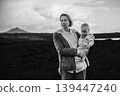 Mother enjoying winter vacations playing with his infant baby boy son on black sandy volcanic beach of Janubio on Lanzarote island, Spain on windy overcast day. Family travel vacations concept 139447240