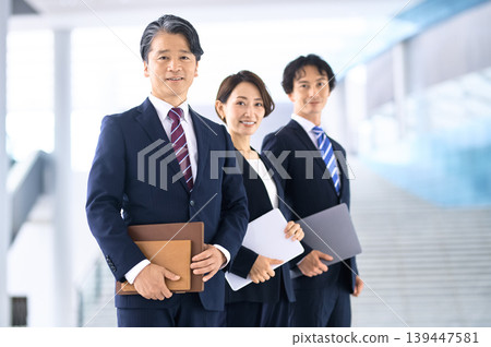 A confident middle-aged businessman and his team of three - indoors A confident middle-aged businessman and his team of three - indoors 139447581
