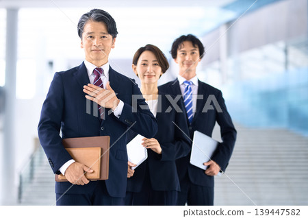 一位中年商人和他的團隊雙手叉腰,自我介紹。 一位中年商人和他的團隊雙手叉腰,自我介紹。 139447582