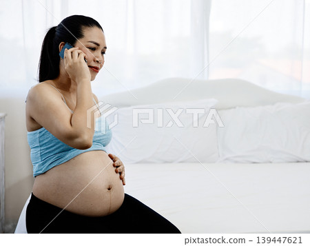 Pregnant woman talking on smartphone while sitting on bed at home, maternity and healthcare concept, expecting mother lifestyle, prenatal care, pregnancy communication and family wellness Pregnant woman talking on smartphone while sitting on bed at home, maternity and healthcare concept, expecting mother lifestyle, prenatal care, pregnancy communication and family wellness 139447621