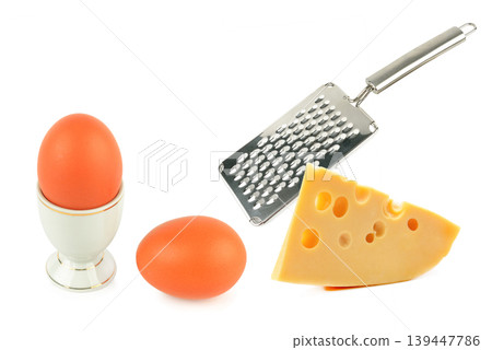 Minimalist kitchen still life with eggs, cheese wedge, and stainless grater isolated on white background. Minimalist kitchen still life with eggs, cheese wedge, and stainless grater isolated on white background. 139447786
