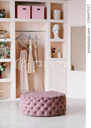 Elegant Pastel Wardrobe Interior With Pink Velvet Ottoman And Evening Dresses Elegant Pastel Wardrobe Interior With Pink Velvet Ottoman And Evening Dresses 139447817