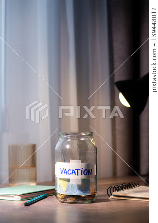 Close up of transparent money jar labeled for VACATION. Represents traditional saving methods and conscious money management for future 139448012