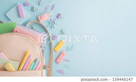 Pastel school supplies spilling from backpack on blue background Pastel school supplies spilling from backpack on blue background 139448147