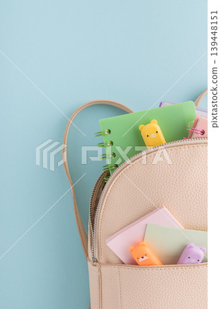 Pastel school supplies into backpack on blue background Pastel school supplies into backpack on blue background 139448151