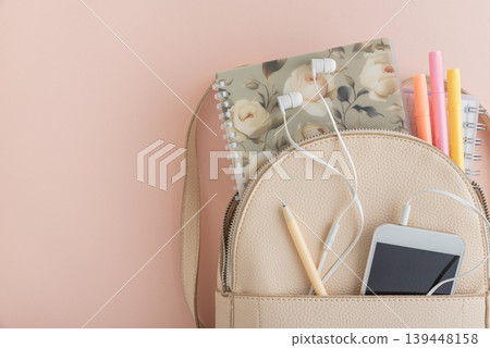 Backpack with notebook, phone, and earphones on pink background Backpack with notebook, phone, and earphones on pink background 139448158