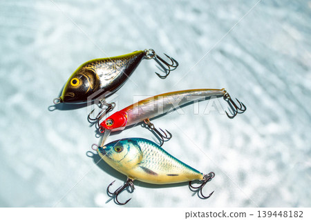 Colorful fishing lures and tackles on blue background with shadow from water, ready for fishing Colorful fishing lures and tackles on blue background with shadow from water, ready for fishing 139448182