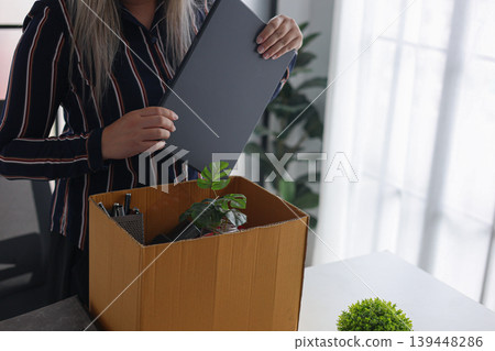 Businesswoman Packing Belongings in Box After Resignation or Layoff. 139448286