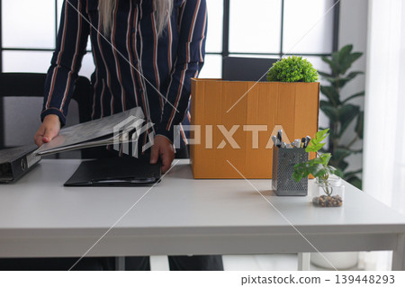 Close-up of Employee Packing Stuff from Working Desk After Quitting Job. Close-up of Employee Packing Stuff from Working Desk After Quitting Job. 139448293